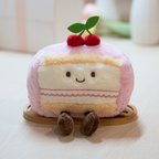 Plush toy resembling a slice of cake with cherries on top, sitting on a wooden stand.