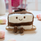 Plush toy resembling a slice of chocolate cake with a smiling face on a wooden base.